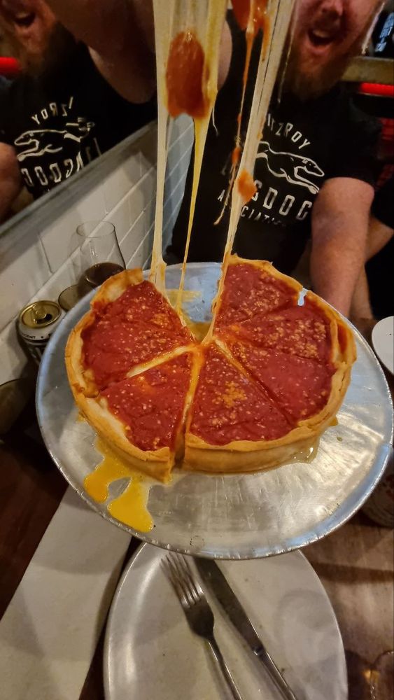 Pask pulls a slice of deep dish pizza. The mozzarella stretches a long way up!