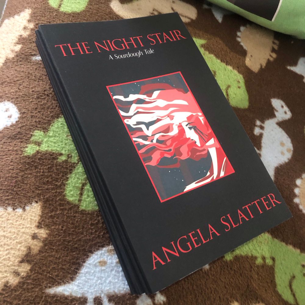 A small pile of Angela Slatter’s The Night Stair chapbook in print, placed on a blanket covered in dinosaurs 

The dinosaurs aren’t thematically linked to the book at all. It’s just the blanket we have at the office right now. 