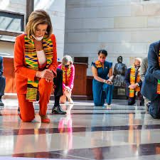 pelosi and friends taking a knee in colorful suits wearing kente cloths