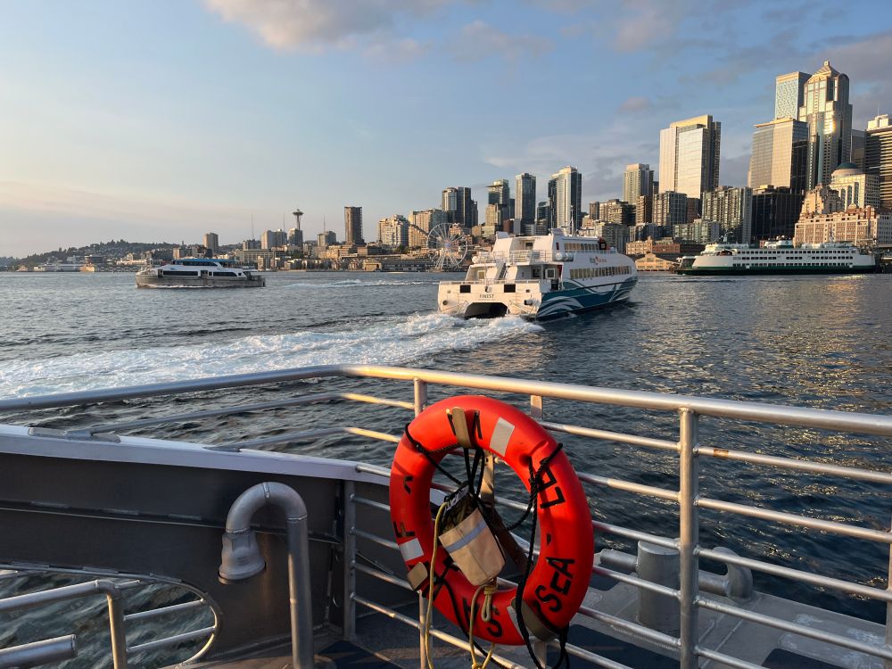 view of downtown Seattle skyline at golden hour from the Water Taxi - there are 3 ferries in view