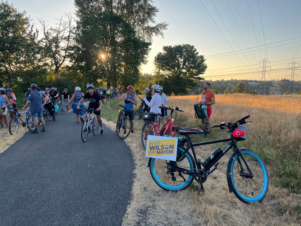 a bunch of people on bikes at golden hour on Chief Sealth Trail - bike in foreground has a Katie Wilson sign