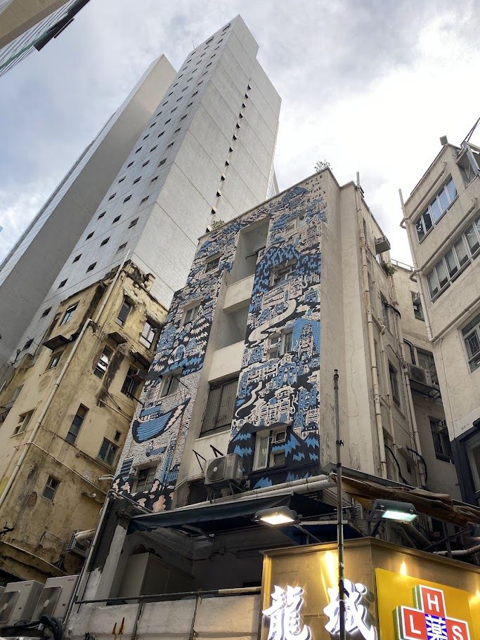 Blue and white mural on the side of a small apartment building in Causeway Bay, Hong Kong
