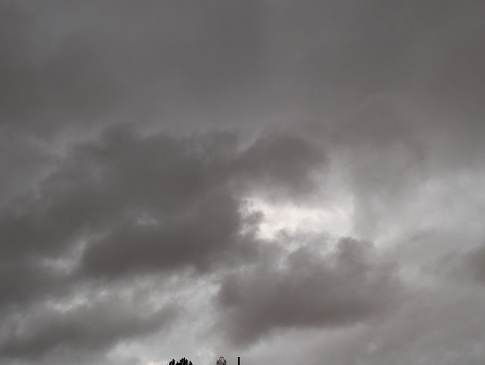 Different grey clouds with a bright spot in the center. The grey varies and is tinged slightly orange due to an approaching storm occluding the sunset