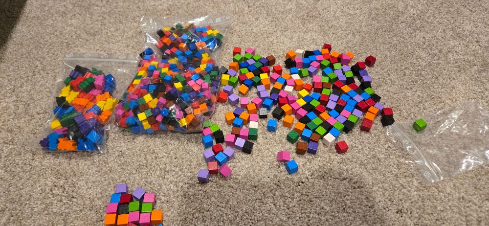 Cubes and locomotives of various colors and sizes in a pile in the floor.