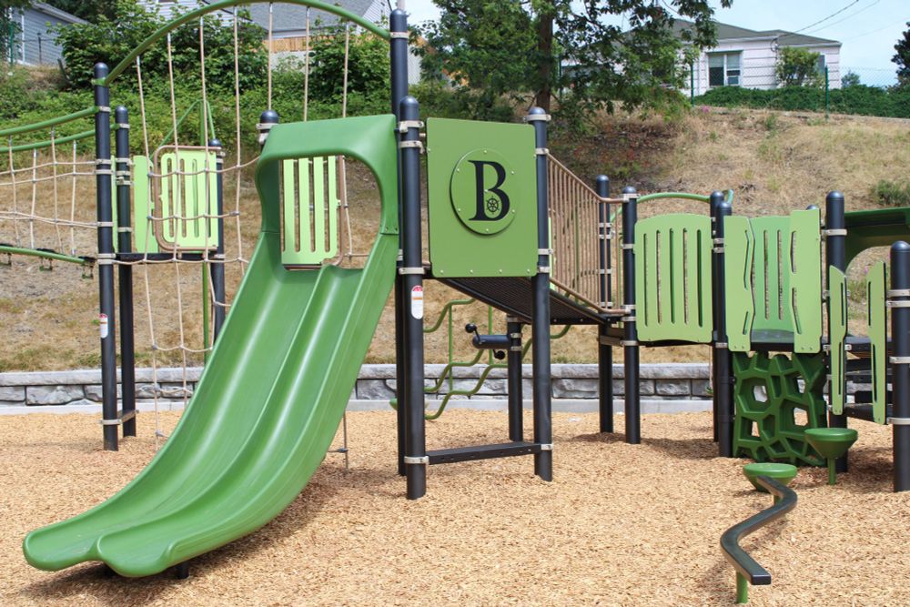 Green playground structure with the City of Bremerton logo stamped on it
