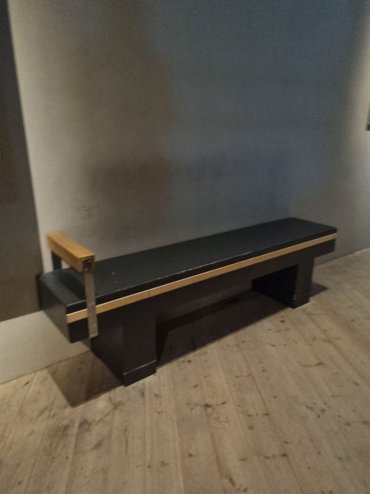 Bench against the wall with one arm (on left of image)