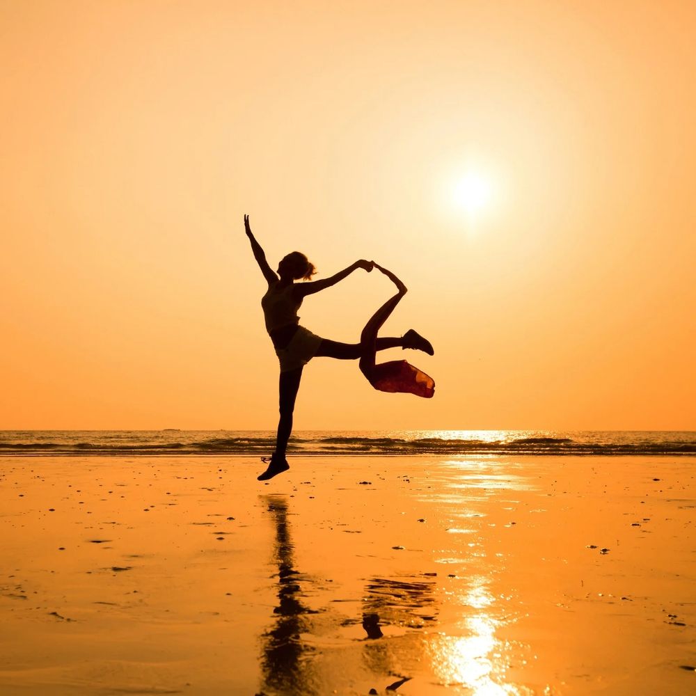 Women's silhouette dancing on the beach in a sunset