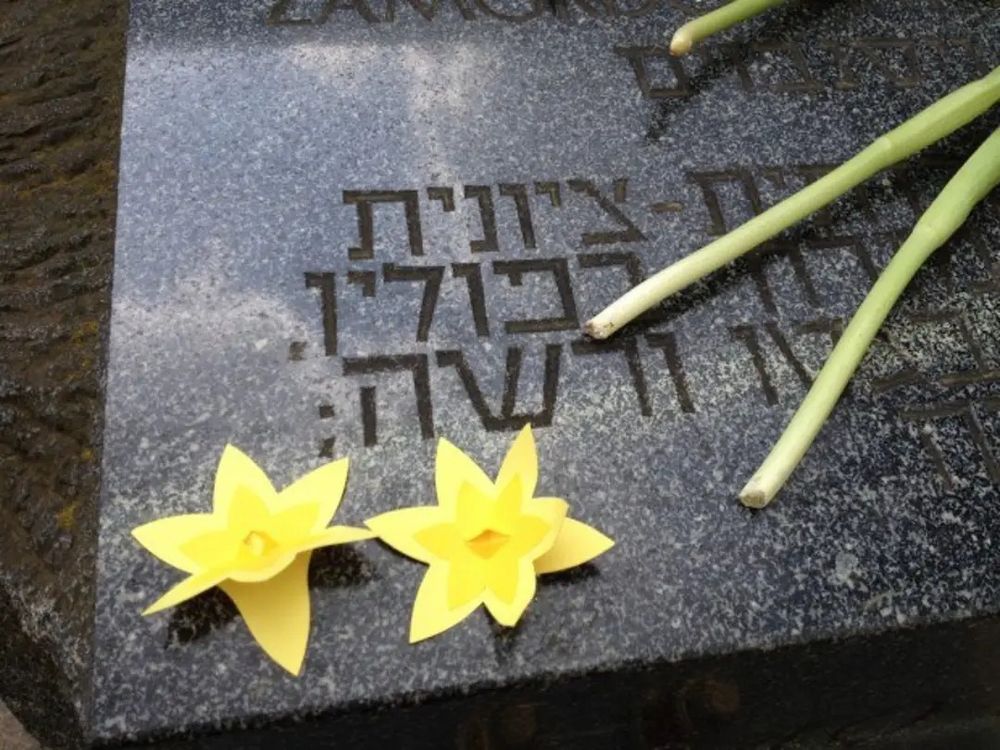 Yellow daffodils on a plate of a monument commemorating the participants of the Warsaw Ghetto uprising of 1943