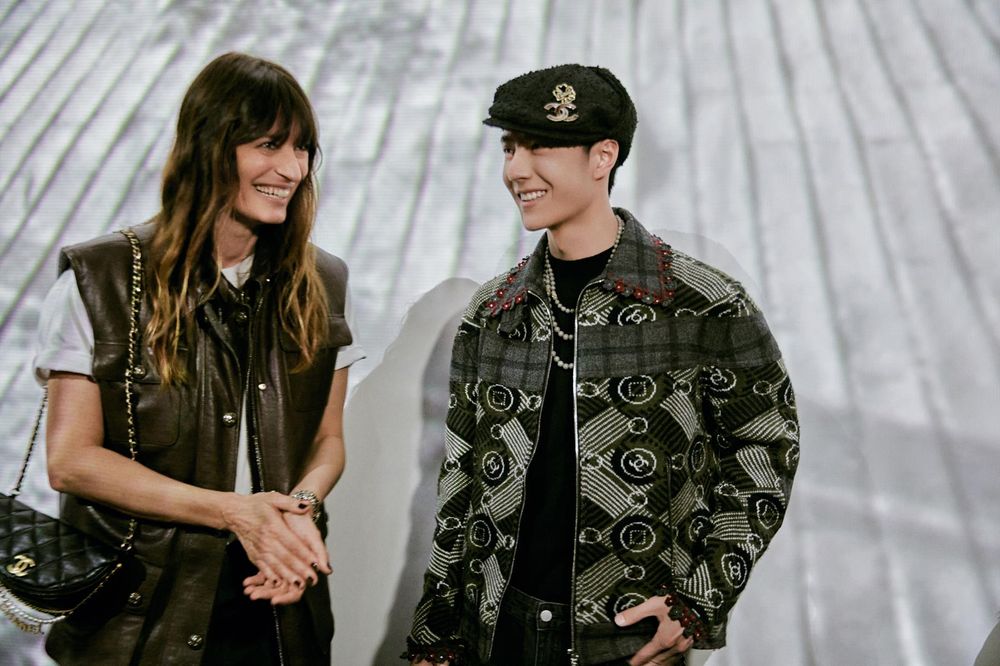Caroline de Maigret and Wang Yibo standing together smiling (photo taken at a Chanel fashion show in Paris.)