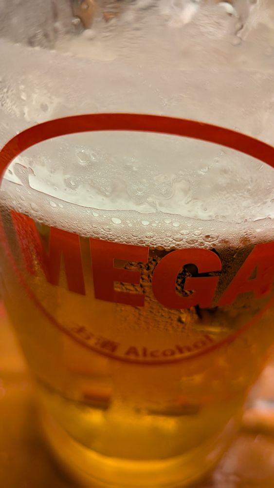 飲みかけのビールの入ったジョッキ。赤い文字でMEGAと書かれている。