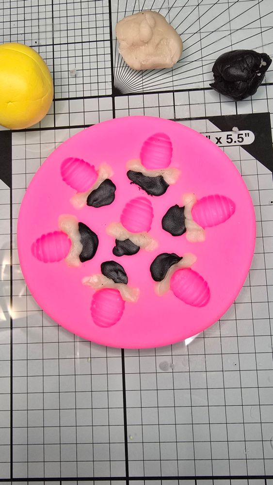 The black clay for the bee heads and translucent clay for the wings is pressed into the mold