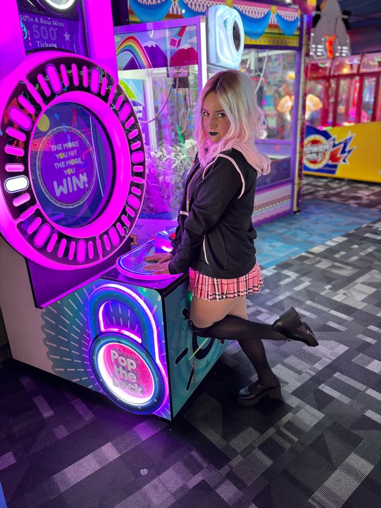 Me cosplaying as Emberlynn from Helluva Boss, posing in an arcade 