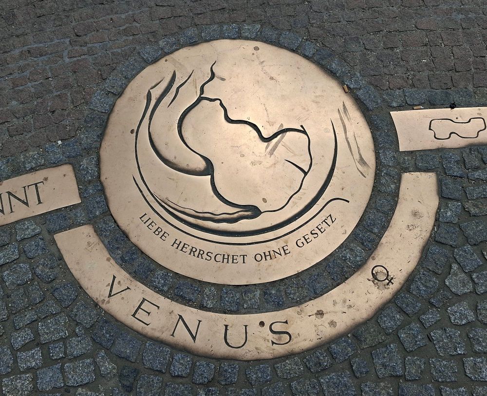 Eine Plakette auf dem Boden mit der Inschrift "Liebe herrschet ohne Gesetz" Darunter in Großbuchstaben VENUS