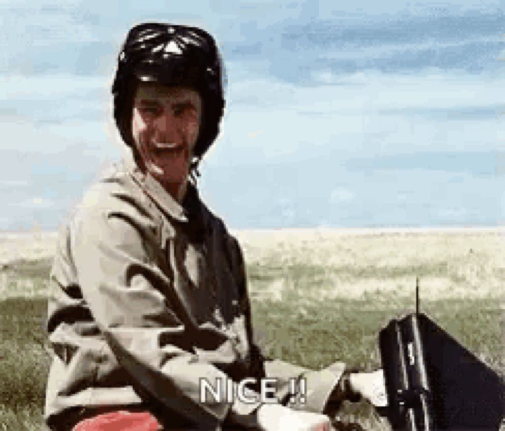 a man wearing a helmet and sunglasses is sitting in a field holding a briefcase .