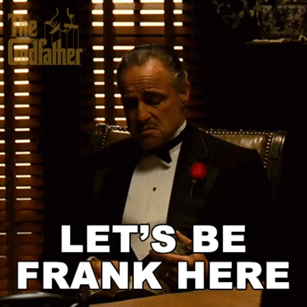 a man in a tuxedo is sitting at a desk with the words let 's be frank here