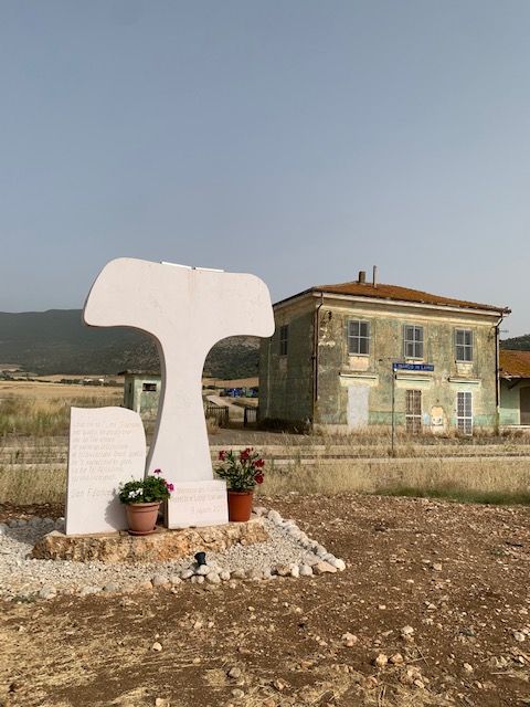 The memorial to Aurelio and Luigi Luciani with the abandoned station of San Marco in Lamis in the background.