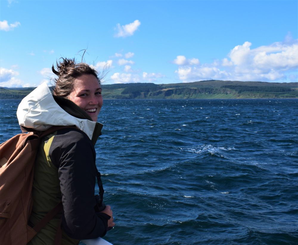 Daisy Burnell on a boat with sea and land in the background.