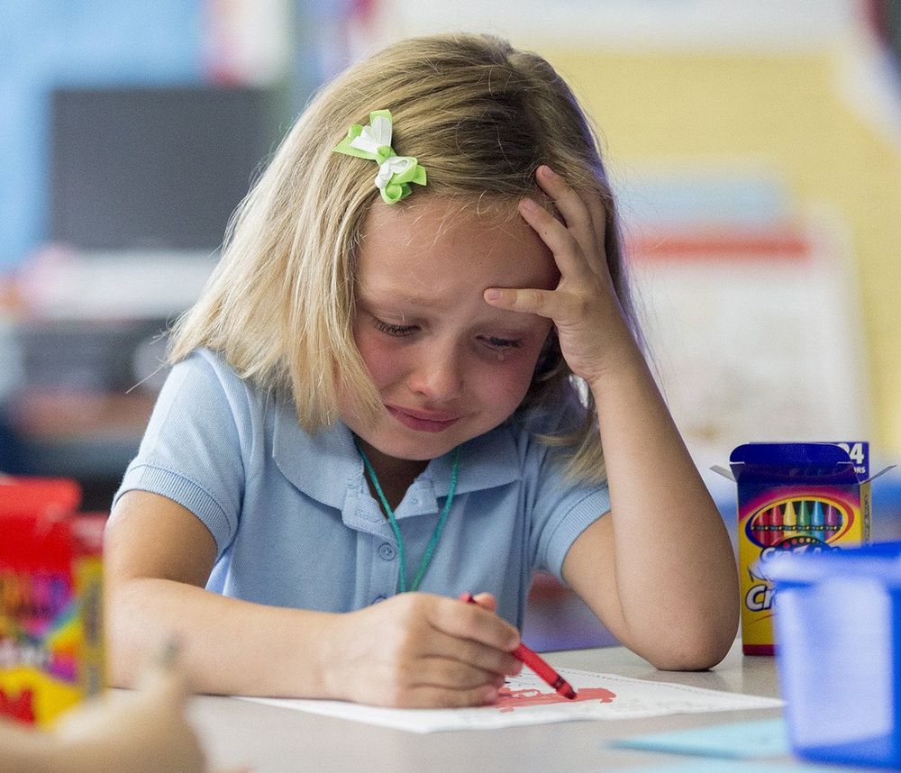 An incredibly stressed little girl is attempting to color at her desk
