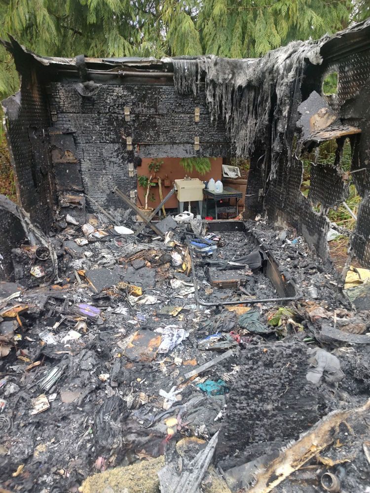 My bedroom and office reduced to ashes. The metal walls and roof are largely destroyed, revealing the forest beyond. 
