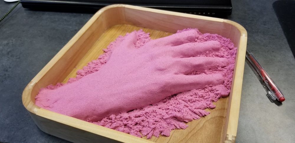 Human hand sculpture in pink Kinetic Sand