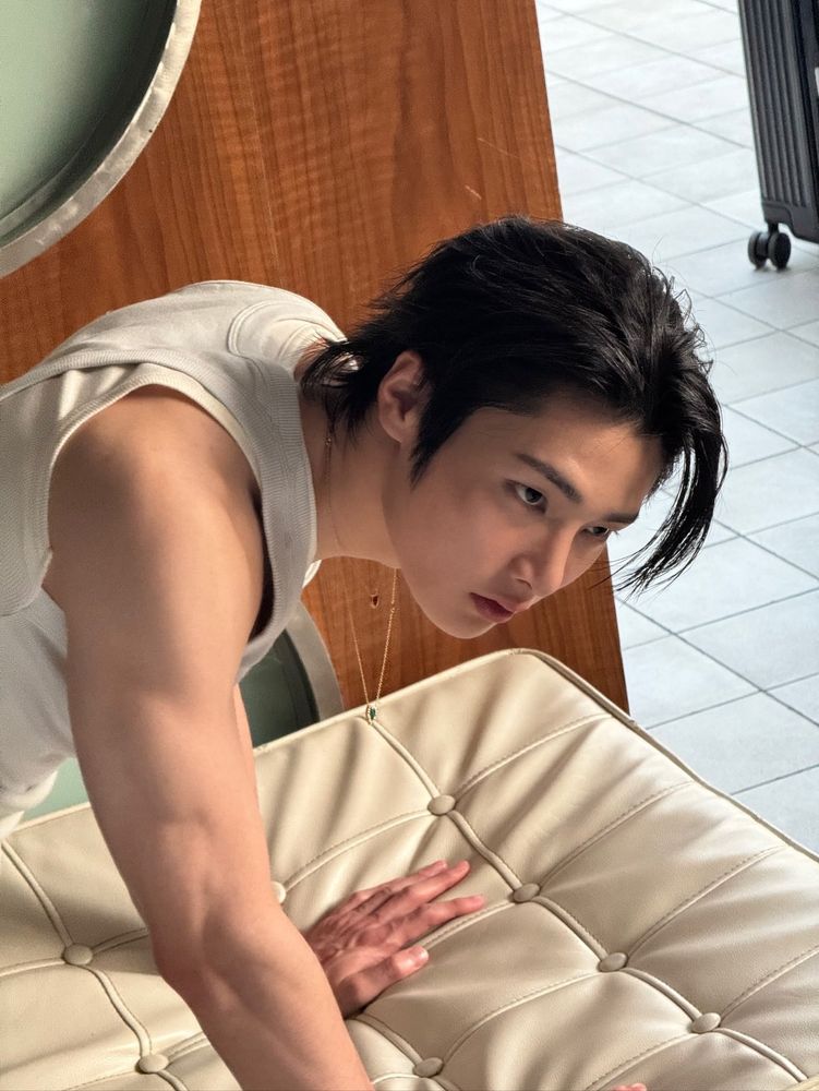 Jeongin posing for cosmopolitan, on all fours on a bed(?) with his necklace dangling, arms bare, and face card going insane