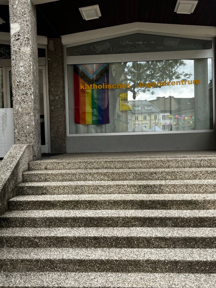 Pride flag hanging inside the window of the Catholic youth centre in Villach.