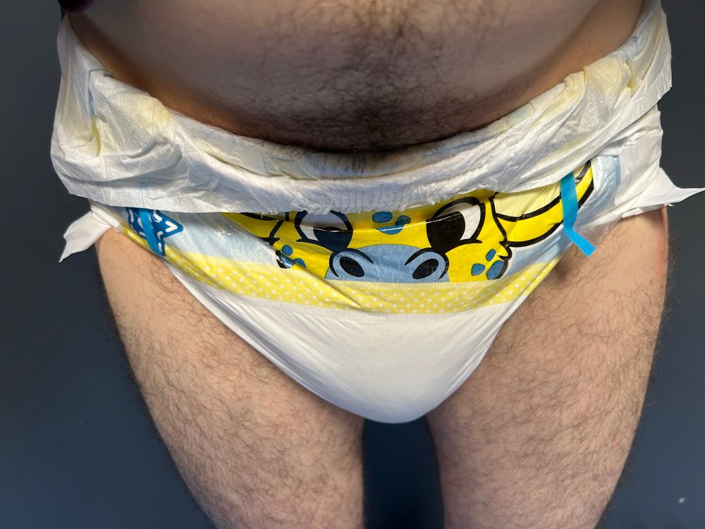 Wearing a soaked yellow giraffe ABU Peekabu diaper, size medium, view of front.