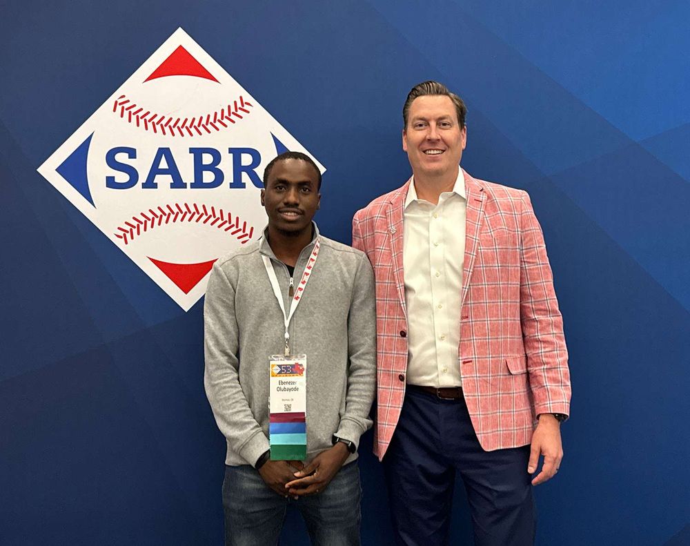 Ebenezer Olubayode in congratulated by SABR CEO Scott Bush after Olubayode won the SABR Convention Poster Presentation Award for the best poster presentation at SABR 53 in Texas.