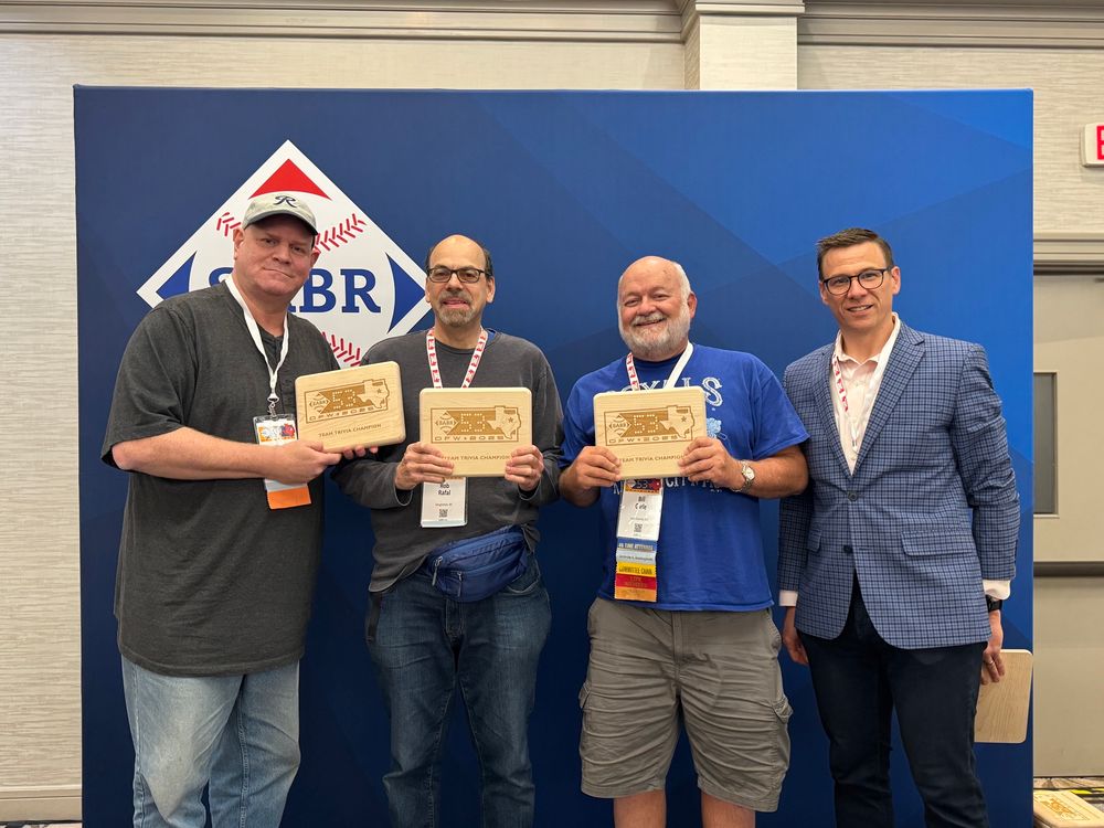 From left, Scott Kent, Rob Rafal, and Bill Carle hold their SABR team trivia plaques along with emcee Dan Massey at SABR 53 in Texas.