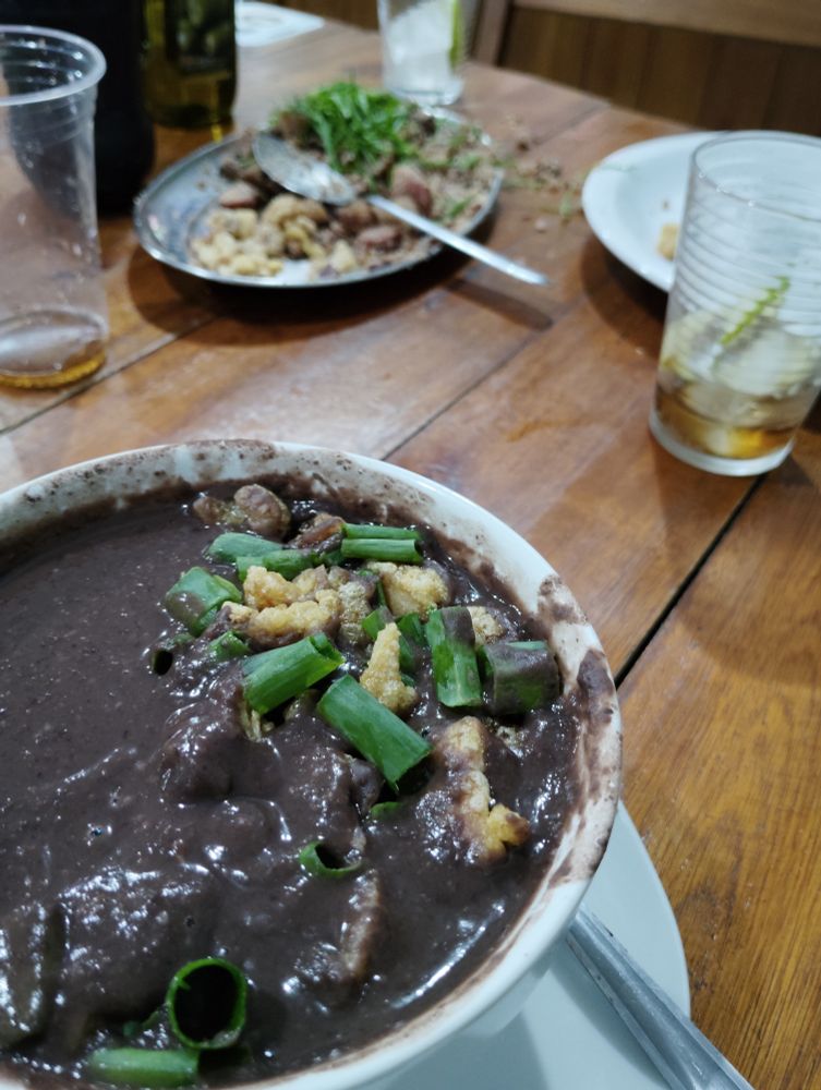 Cumbuca de feijão amigo com tropeiro ao fundo 