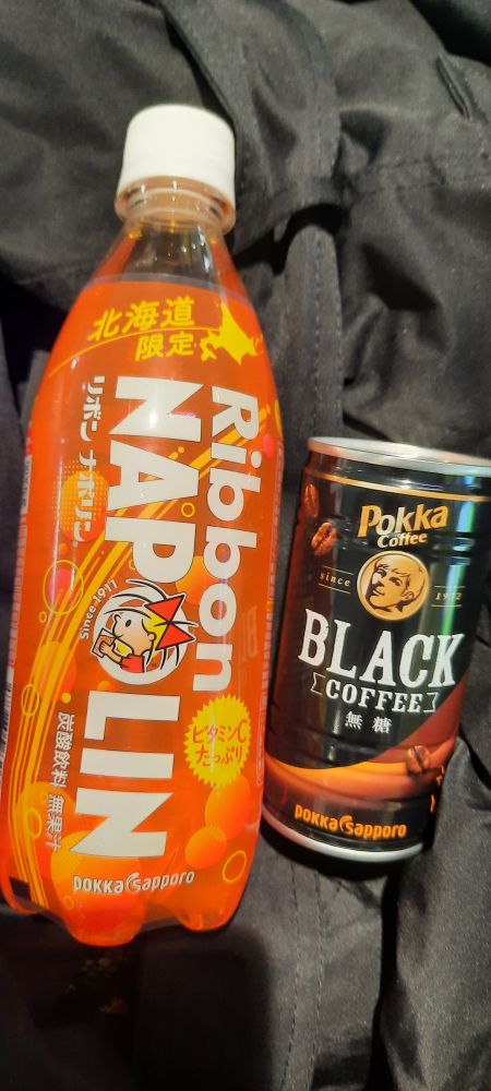 An orange bottle Ribon Napolin  and a small black can of coffee