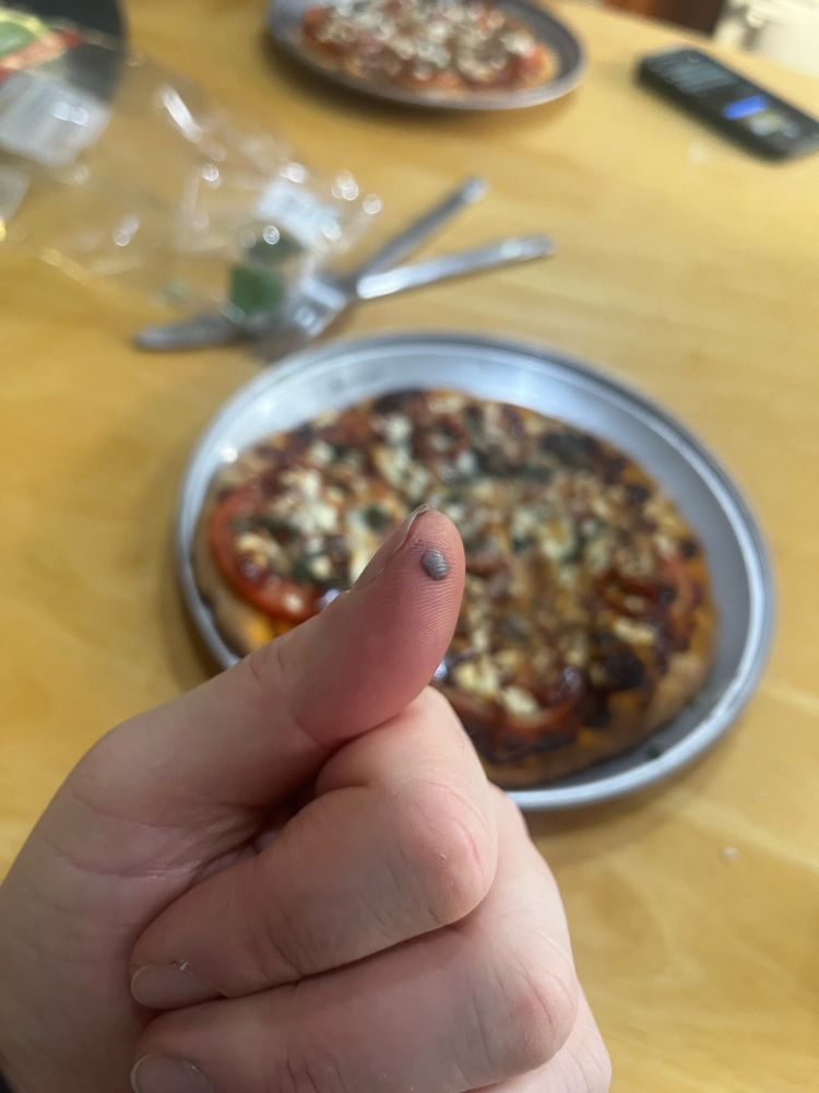 a blood blister on a thumb, photographed in front of pizza