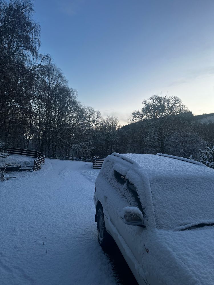 a snow-covered car in a snowy driveway 