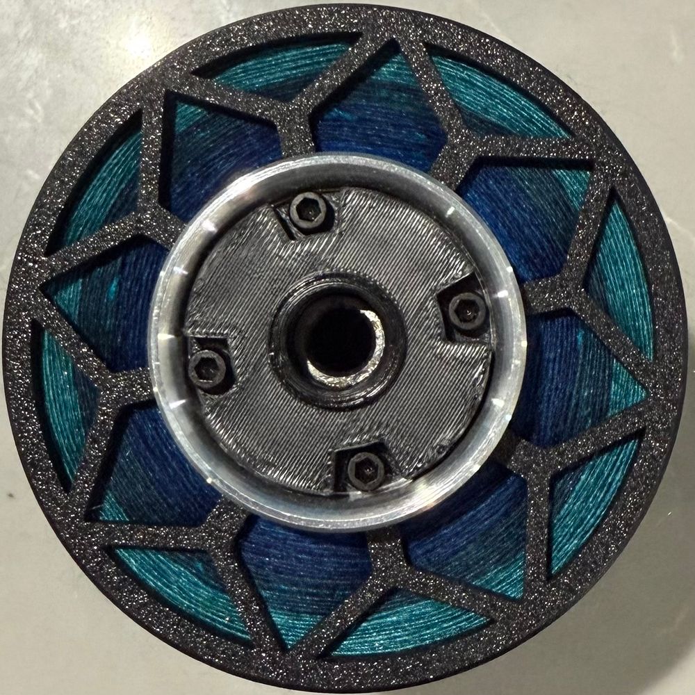 The end of a bobbin showing color transitions from navy to lighter teal.