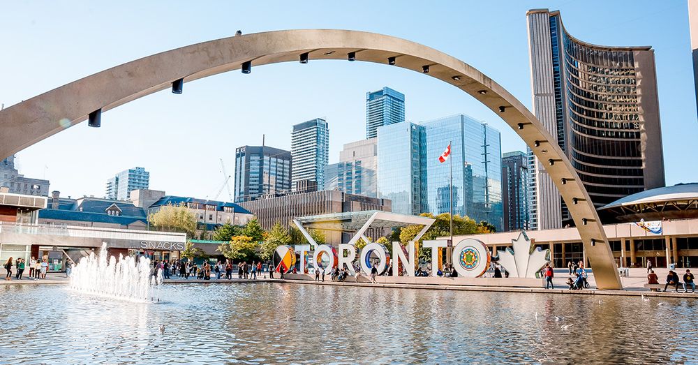 Toronto City Hall with fountain and Toronto sign in foreground and skyline behind