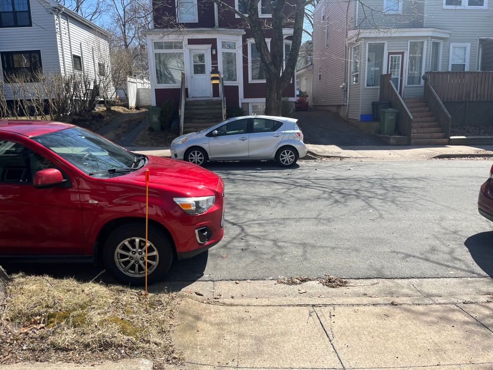 A red car parked slightly in front of a driveway 