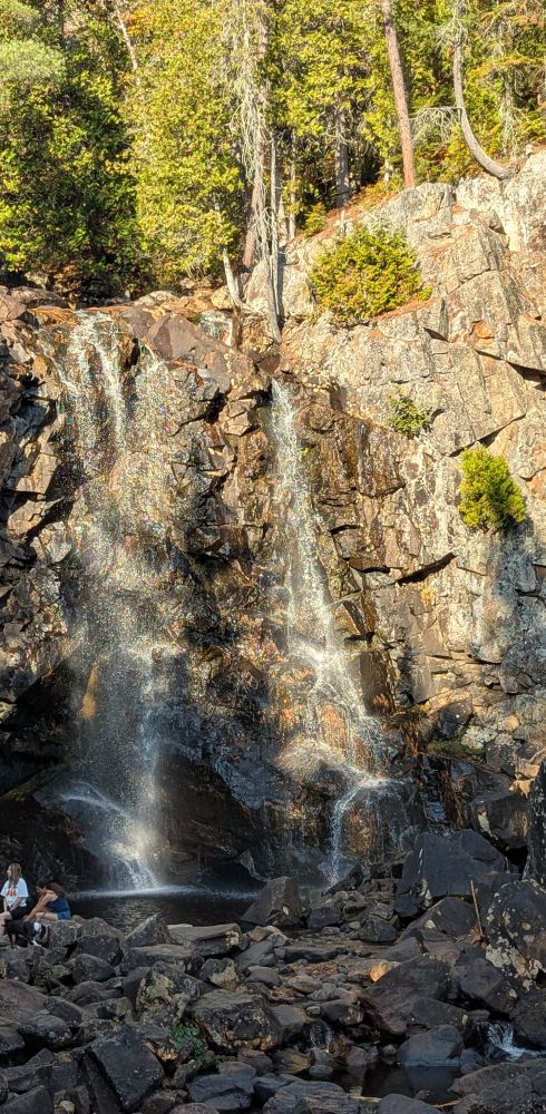 Waterfalls falling into a little pool with a bunch of rocks.
