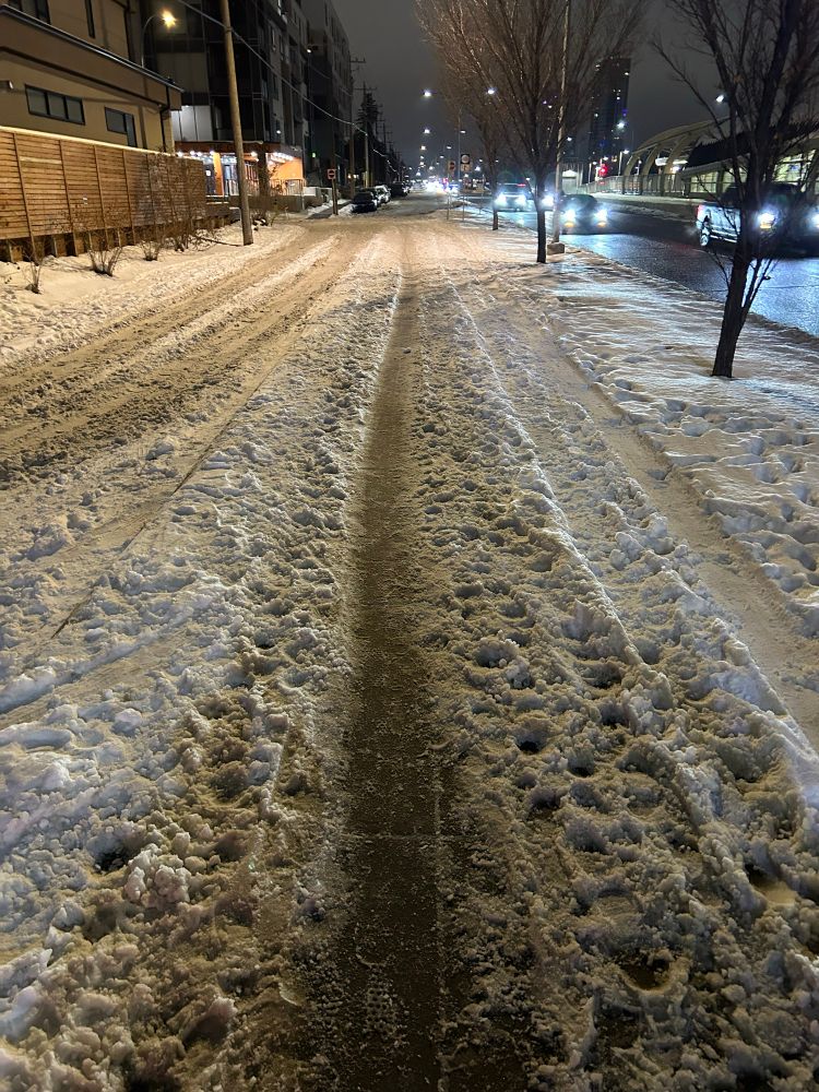 Poorly maintained city sidewalk covered in loose snow
