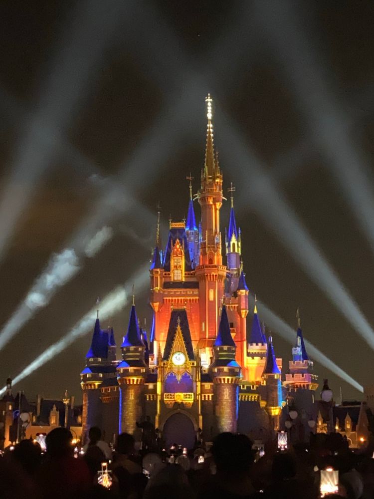 Nighttime photo of Cinderella’s Caste at Disney World’s Magic Kingdom.  The castle is lit with spotlights because the fireworks and light show is about to begin.