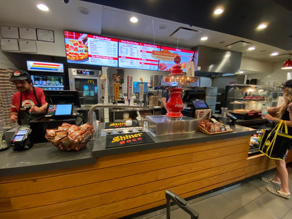 Photo from inside the DFW Terminal C Pizza Hut showing the order counter and draft beer taps.