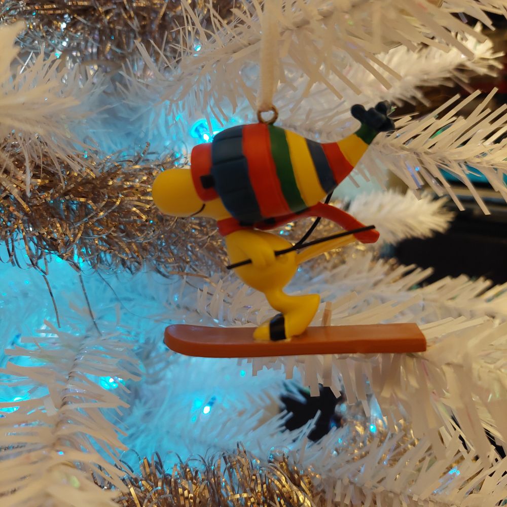 Woodstock, on a ski, wearing goggles and a colorful knit cap, against the same background 