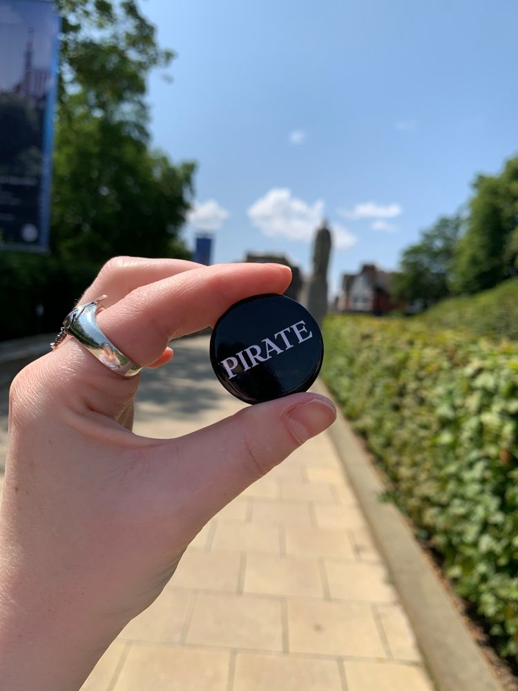 black button badge with the word “pirate” written in white