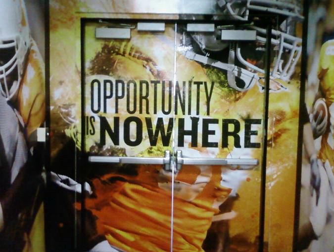 Locker room signage meant to say “Opportunity is Now Here” which is weird phrasing as it is, but due to poor spacing choices it says “OPPORTUNITY IS NOWHERE”
