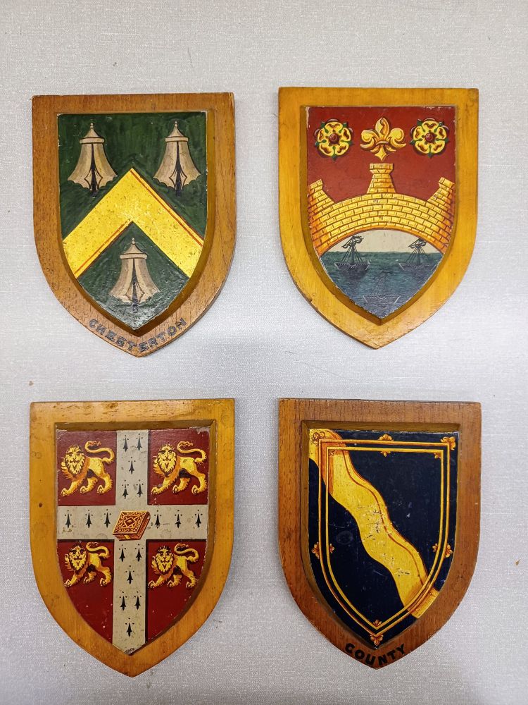 Four small wooden coat of arms. Clockwise from the top right are hand painted coat of arms for the city of Cambridge, the county of Cambridgeshire, the University of Cambridge and Chesterton. 