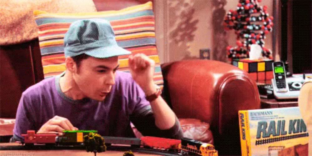 a man wearing a hat is playing with a train set .