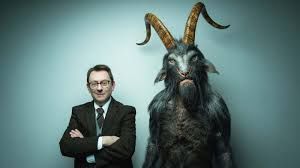 Actor Michael Emerson pictured as his character on the tv show Evil posing with what appears to be a demon or the devil.