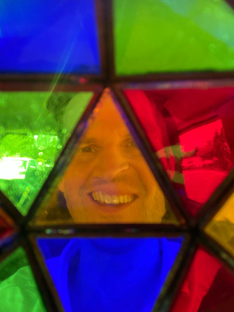 A face distorted through a picture taken through a stained-glass icosahedron.