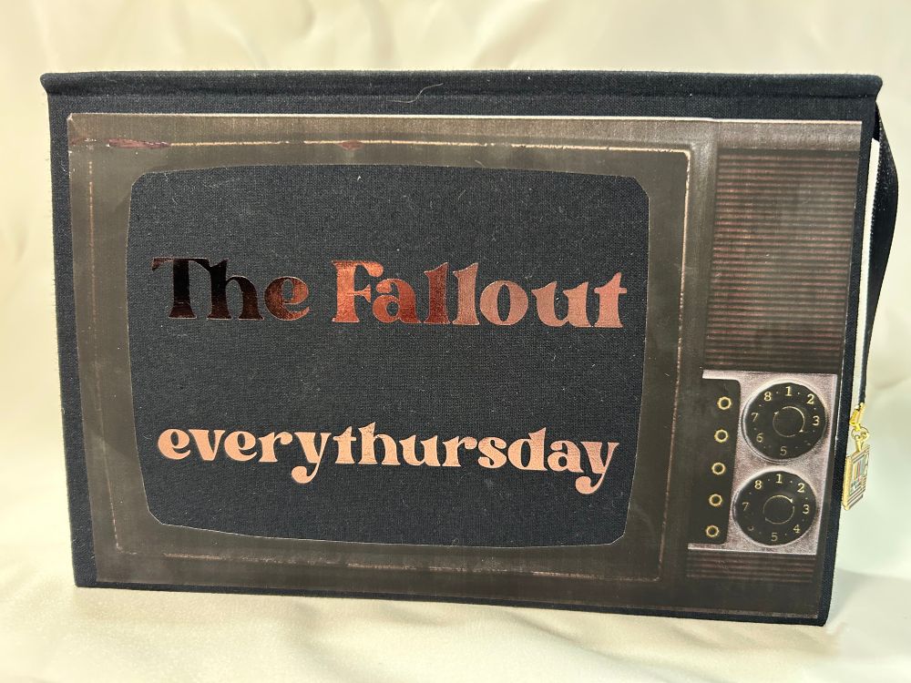 Cover of The Fallout fanfic bind on its side to look like an old school TV set. Words on cover say “The Fallout” and “everythursday” in brown metallic foil. 