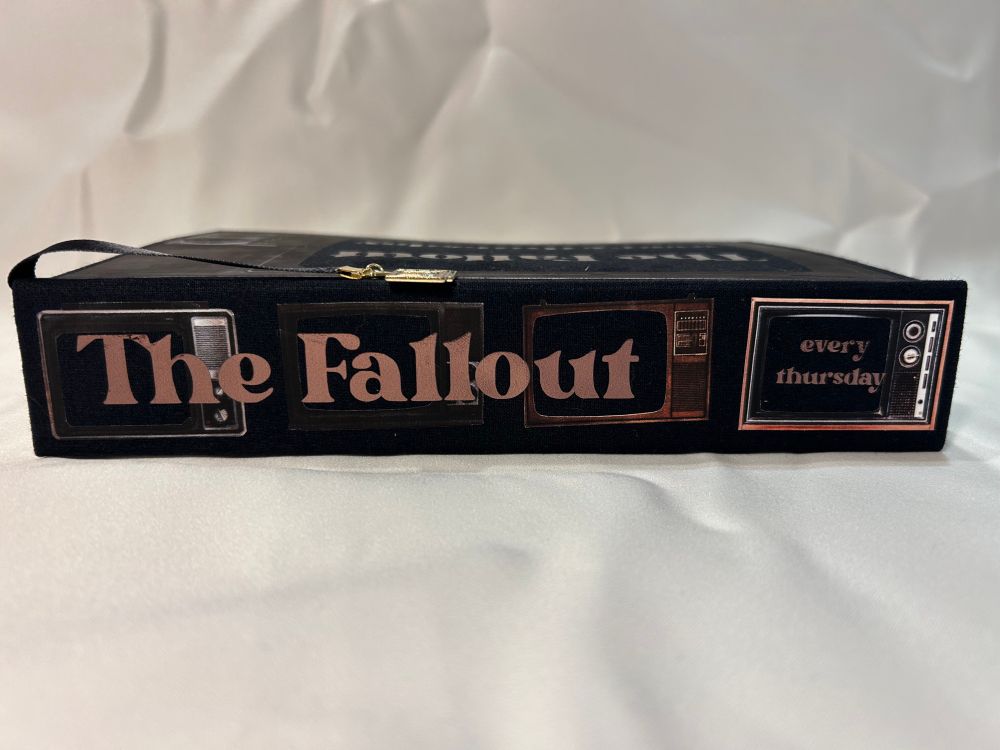 Spine of The Fallout fanfic bind with retro TV silhouettes and “The Fallout” and “everythursday” in brown metallic foil over the tv silhouettes 