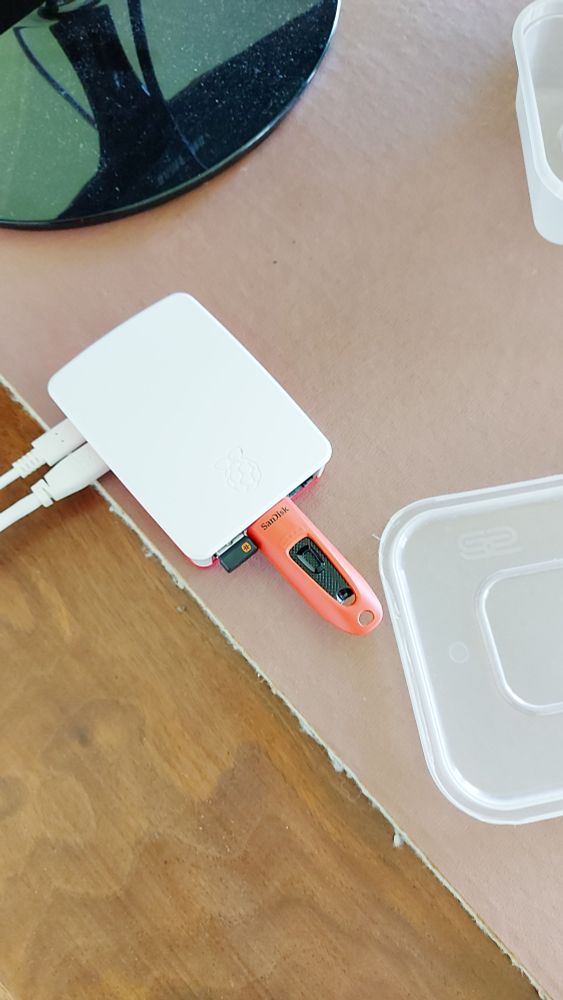 A Raspberry Pi micro computer on a table with a red memory stick inserted. Saved the day when I realised I hadn't properly got the BIOS upgrade prepared for my new Motherboard